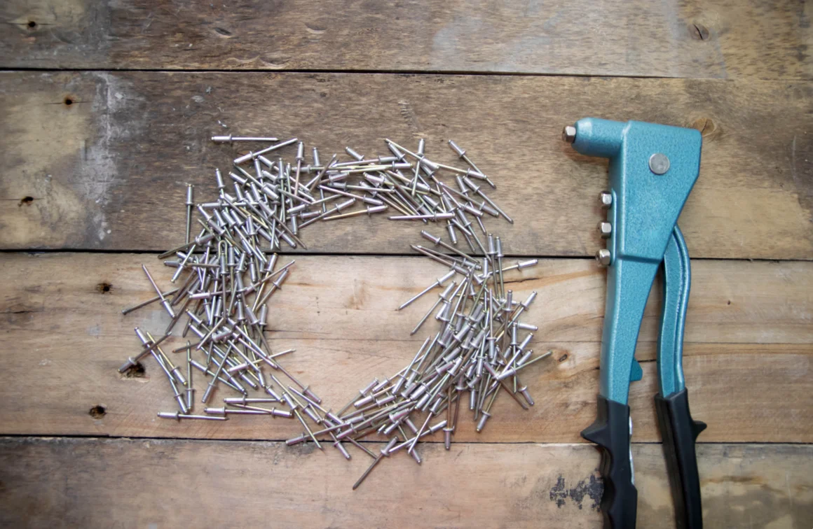 Nietzange und Nieten auf Holz.